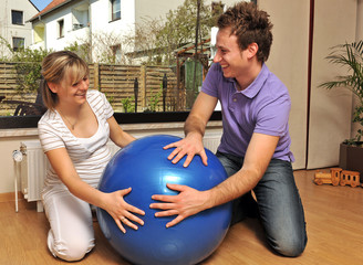 Schwangere Frau und werdender Vater mit Gymnastikball