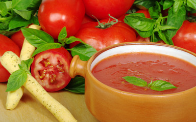 Tomato soup in bowl, tomatoes and basil