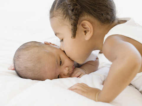 African girl kissing newborn baby sibling