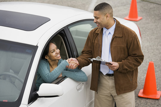 African teenager shaking hands with driving instructor