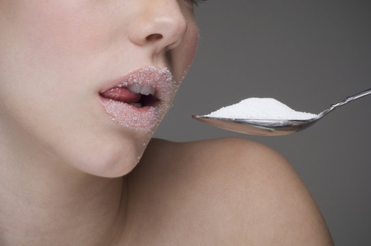 Woman eating spoon of sugar
