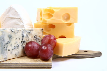 Various types of cheese and some red grapes in close up