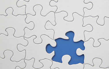 white puzzle with one piece missing, on blue