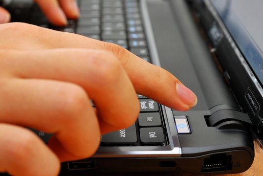 Finger pressing power button on laptop