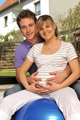 Schwangere Frau und werdender Vater mit Gymnastikball