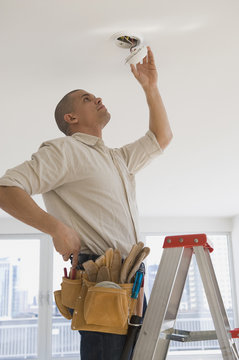 Hispanic male electrician fixing looking at wiring