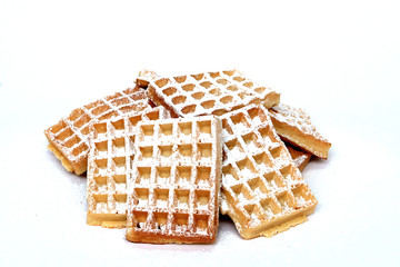 Ein Berg Waffeln auf weißem Untergrund mit Puderzucker