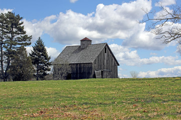 Old barn in field with bright cloudy sky