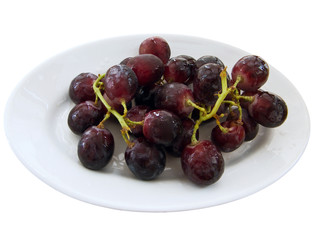 Bunch of black grapes on a white dish.