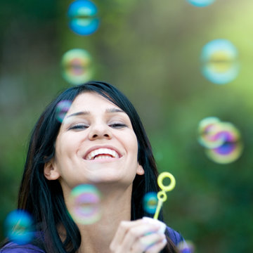 Smiling lady blowing bubbles