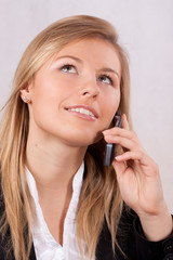 Business woman with mobile phone looking up and smiling - obrazy, fototapety, plakaty
