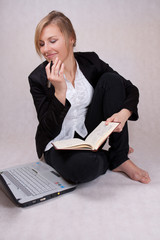 Young business woman writing notes with laptop and smiling - obrazy, fototapety, plakaty