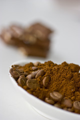 Fototapeta na wymiar Coffee beans and ground coffee with chocolate on the background.