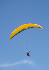paraglider flying under beautiful blue sky