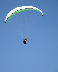 paraglider flying under beautiful blue sky