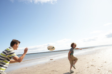 Two Teenage Boys Playing Rugby On Beach Together