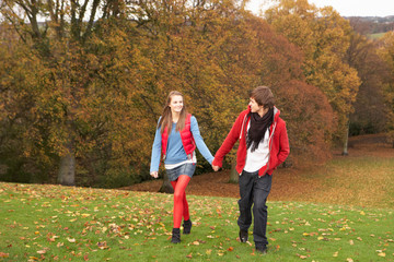 Romantic Teenage Couple Walking Through Autumn Landscape