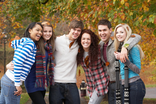 Group Of Six Teenage Friends Having Fun In Autumn Park