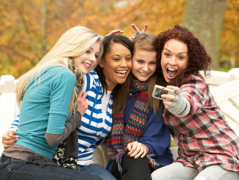 Group Of Four Teenage Girls Taking Picture With Camera Sitting O