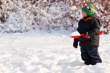 Fototapeta na wymiar Little boy playing with snow in winter forest