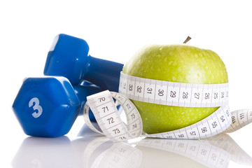 Dumbbells, fresh green apple and measure tape