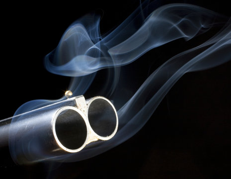 both barrels smoking on a double-barreled shotgun with a black background