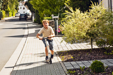 child with scooter on a pedestrian path