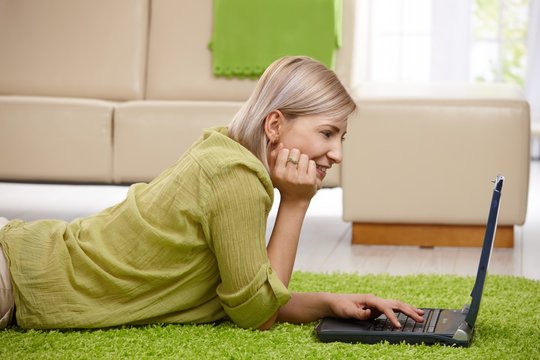 Smiling woman with computer at home