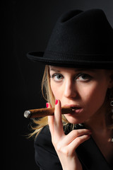 Beautiful girl in a hat smoking a cigar