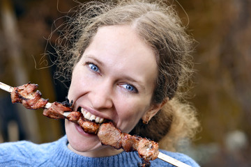 The girl on picnic eats meat kebab