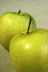 Two green apples on a linen tablecloth