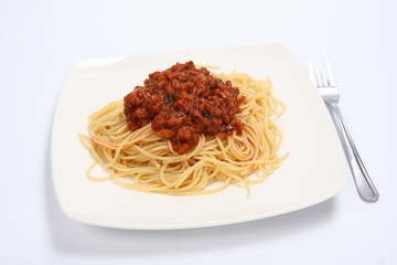 Pasta with bolognese sauce on a plate and a fork on white