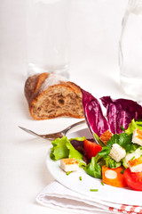 gemischter Salat auf einem weißen Teller mit einer Gabel