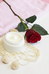 Obraz na płótnie Canvas Container of cosmetic cream with rose, pearl necklace