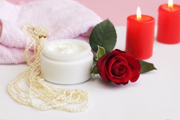 Fototapeta na wymiar Container of cosmetic cream with rose and pearl necklace