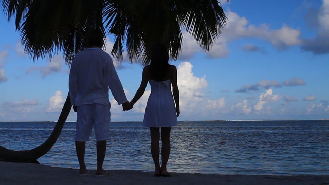 Romantic couple standing next to palm tree