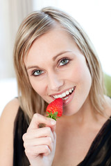 Radiant woman eating a strawberry