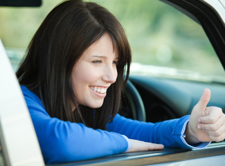 Fototapeta na wymiar Smiling teen girl with a thumb up sitting in her car