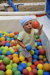 Fototapeta na wymiar funny boy plays with varicoloured balls in playground