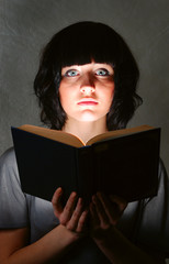 young beautiful woman is illuminated by a glowing book