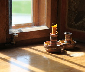 Unlit candle in the church in front of a  fenster