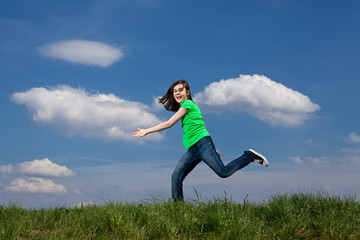 Girl jumping, running against blue sky