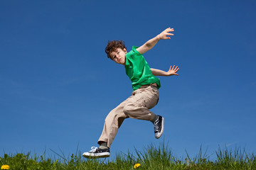 Girl and boy jumping, running against blue sky