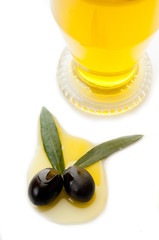 black olives with leaf over oil and bottle of oil