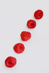 Raspberries in a row on a white background