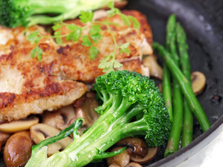 fried breaded fish with vegetables in a black pan