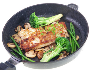 fried fish with vegetables in a black pan isolated on white