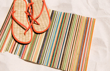 Beach mat and shoes on sand