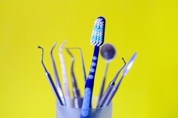 Toothbrush and dental instruments in a glass - obrazy, fototapety, plakaty