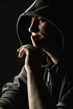 Hooded man holding a finger to his mouth